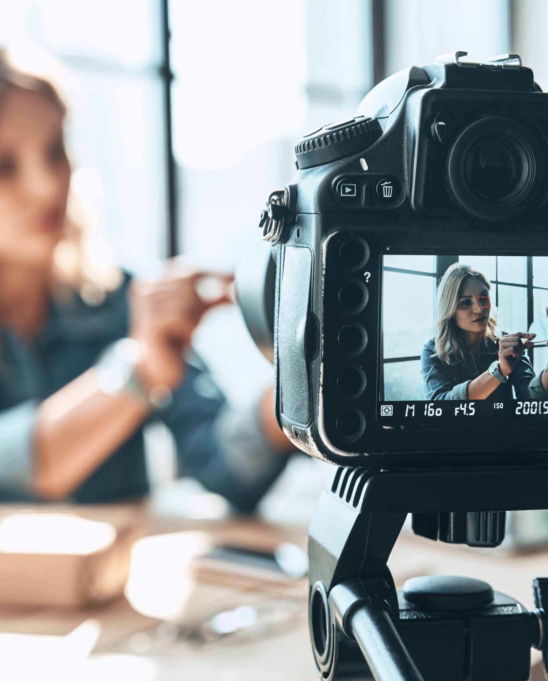 Her new video is awesome. Beautiful young woman in casual wear recording video while sitting indoors